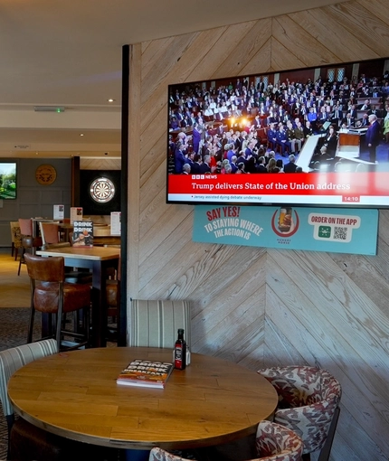 The interior restaurant seating area at The Steam Turbine, with TVs on the walls, and a dartboard.