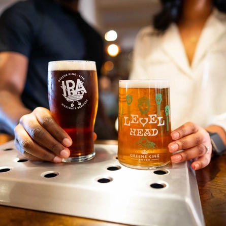 A close up image of a pint of Level Head and a pint of Greene King IPA sat on the interior bar at a Community Pubs With Food venue.