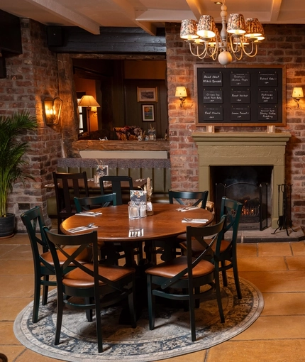 The interior restaurant seating area at The Malthouse Farm in Whittle-Le-Woods, with a fireplace and stone flooring.
