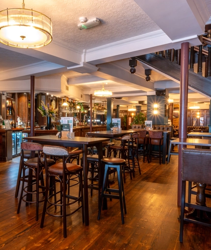 The bar and interior restaurant seating area at the Lord Raglan in Holborn, with a TV on the wall, and a staircase leading to the upper floor.