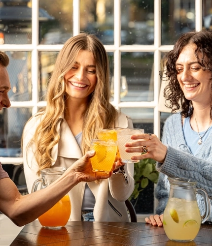 People drinking cocktails, pouring out of jugs into lowball glasses.