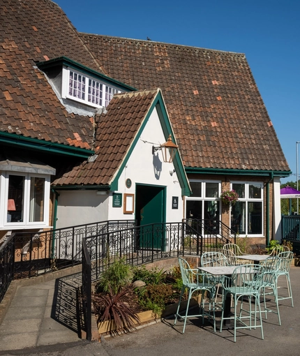 The exterior facade, seating area, and disability-friendly main entrance of the Rudds Arms; with an accessibility ramp leading up to the door.