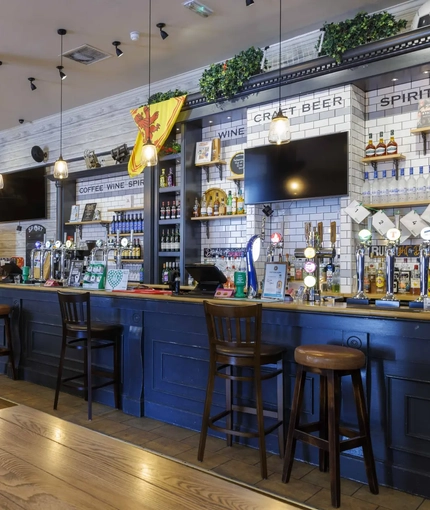 Interior dining area of a pub with TVs and a bar.