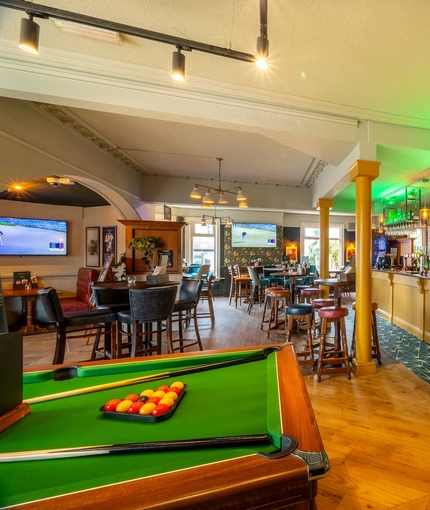 The bar and interior restaurant seating area of the Malvern Tavern in Shirley, with TVs on the walls, and a pool table.