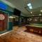 The interior games area at the Lord Raglan, with wooden floor, pool tables, a dartboard, and TVs on the wall.