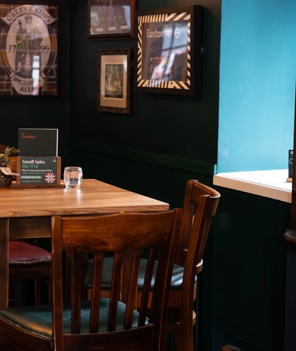An interior restaurant seating area at the Royal George in Euston; with an upholstered booth seat, and framed artwork on the walls.
