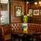 An interior restaurant seating area at The Plough in Bloomsbury, with a semi-circular upholstered booth seat, and framed artwork on the wood panelled walls.