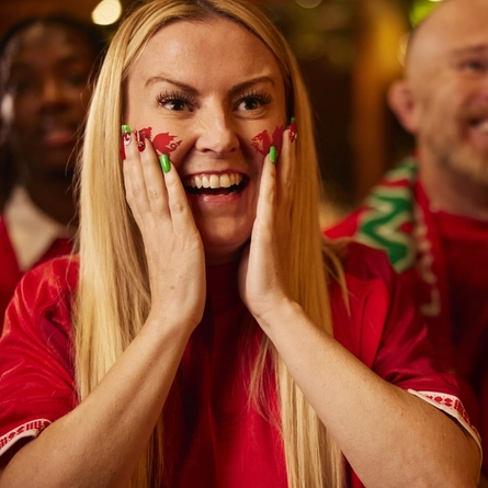 An image of a woman wearing a sport team shirt, watching a sporting event.