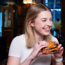 Two people sat in the interior restaurant and seating area in a Urban Social venue, enjoying burger main meals and drinks.
