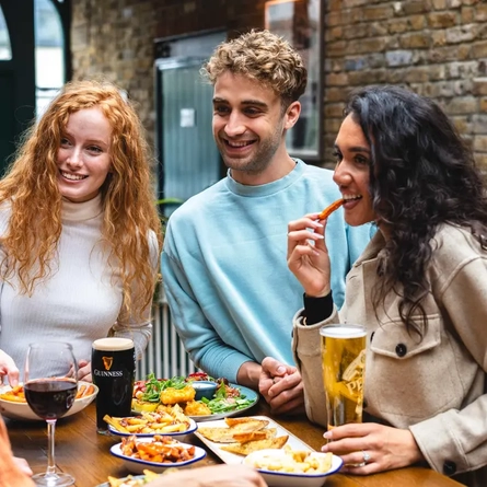 People standing around food eating and drinking