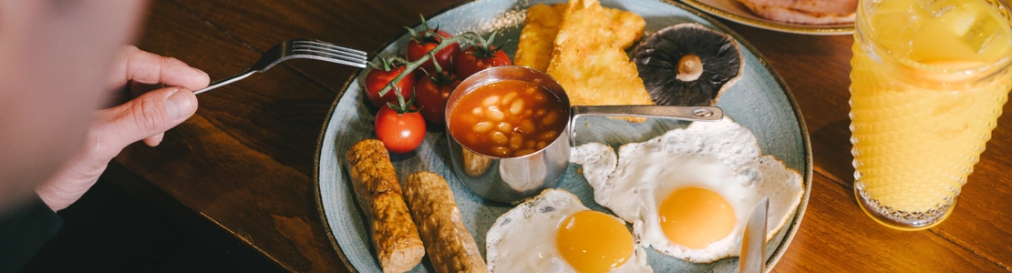 A lifestyle image showing 2 customers enjoying Full English Breakfast's with coffee and fruit juice within the interior restaurant seating area at Urban Core Venues.