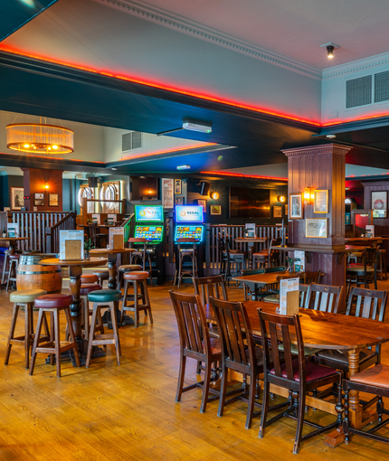 The interior restaurant seating area and bar at the Scholars Arms in Southampton; with illuminated dartboards, TVs on the walls, and gaming machines.