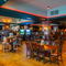 The interior restaurant seating area and bar at the Scholars Arms in Southampton; with illuminated dartboards, TVs on the walls, and gaming machines.
