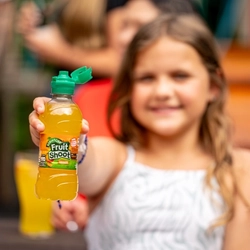 A blurred image of a young girl holding an in-focus image of a bottle of Fruitshoot in front of her.