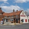 The exterior facade, signage, and seating area at The Vine Inn in Ower, with small trees in wooden planter boxes.