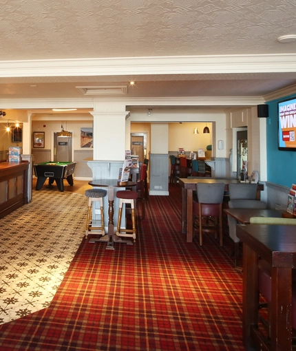 Interior dining area of a pub with a bar and a TV.