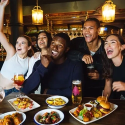 Friends cheering in the pub whilst eating and drinking
