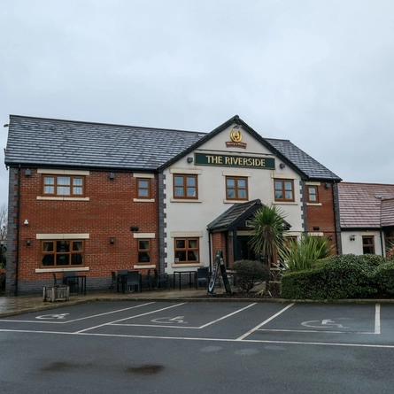 The exterior facade and outdoor seating area with car park at The Riverside.