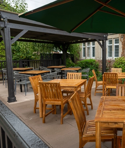 The exterior patio beer garden seating area with wooden tables, chairs and advertising signage at The Church View Inn.
