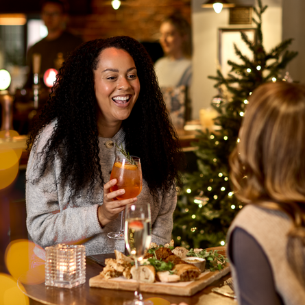 An image of 2 people enjoying a sharing platter and drinks within the interior restaurant and seating area at a Chef & Brewer venue.