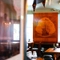 An interior restaurant seating area at the Royal George; with a TV on the wall, a fireplace, and a large wooden inlay picture of a sailing ship on the wall above it.