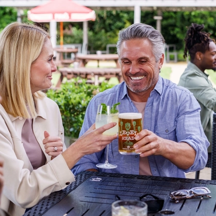 A mixed group of people, sitting at an outdoor table, enjoying a variety of drinks and conversation.