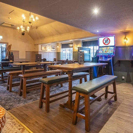 An image showing the interior bar and restaurant seating area with bar stool seating, tables, chairs, cushioned seating benches and electronic pub gaming machines at The Sportsman.