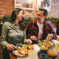 An image of 3 people enjoying various main dishes and a selection of drinks while sat within the interior restaurant seating area.