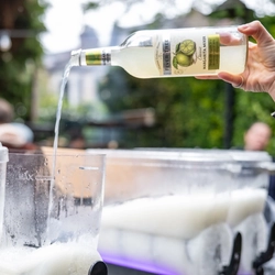 An image focusing on a bottle of Fever Tree being poured into an ice machine by a member of staff working behind the exterior bar during The Boat Race event at The Crabtree.