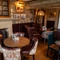 An interior restaurant seating area of The Hollybush, with upholstered chairs, wooden beams, and a fireplace.