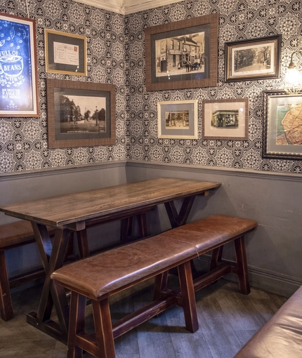 Interior decor featuring patterned wallpaper, framed artwork, and a bench.