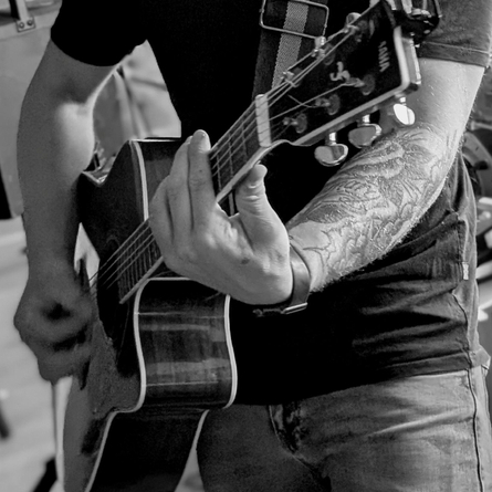 An close up image focusing on a guitar being played to advertise a live music What's On Event at The Cart & Horses.