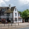 A view from across the road of the exterior facade, signage, seating area, and car park of The Amington in Tamworth.