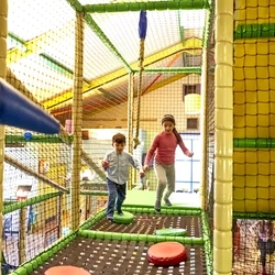 children in indoor play area jumping onto cushioned pads