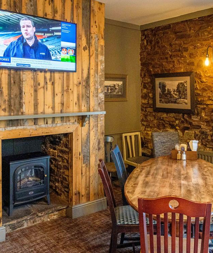 Interior dining area of a pub with a TV and a fireplace.