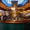A close up view of the U-shaped bar at the Golden Hind in Cambridge, with leaded windows visible through an oval shaped opening in the ceiling above the bar, mirroring the shape of the counter.