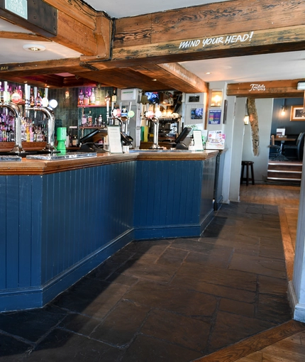 The bar area of The White Hart, with some stools around it.