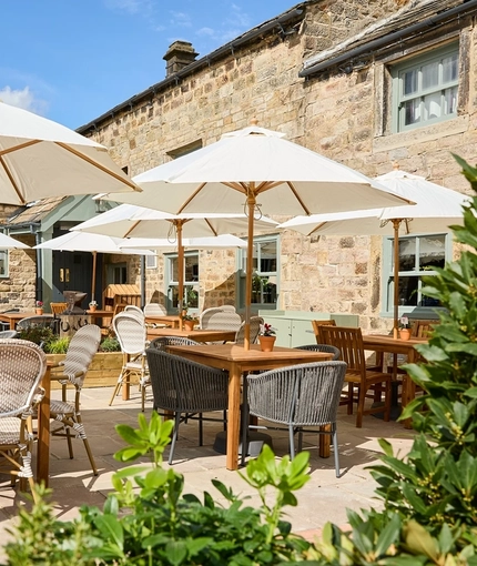 The exterior beer garden seating area of the Smiths Arms pub in Beckwithshaw, with shade umbrellas, plants, and wooden furniture.