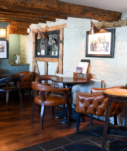 The restaurant area of The White Hart, with a fireplace amongst the tables.