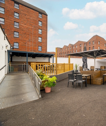The exterior beer garden seating area at the Counting House, with large shade umbrellas, an under cover section, and an accessibility ramp.