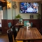 An interior restaurant seating area at The Ship; with plants and a box of board games sitting on the windowsill, and a TV on the wall.