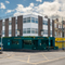 The dark green exterior facade, golden yellow signage, and exterior seating area at The Junction in Upminster, with a view of the neighbouring buildings.