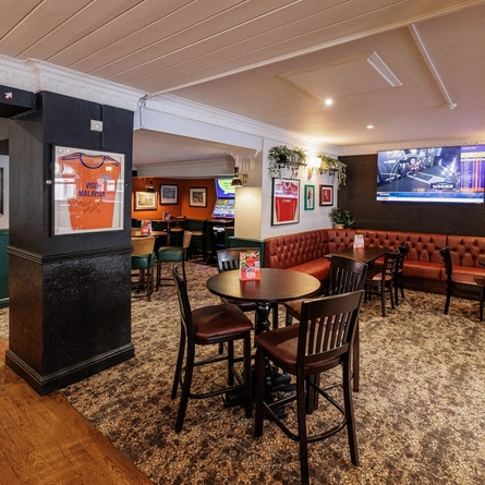 The interior restaurant seating area with tables, seating, electronic pub game and wall mounted TV at The Clive Arms.