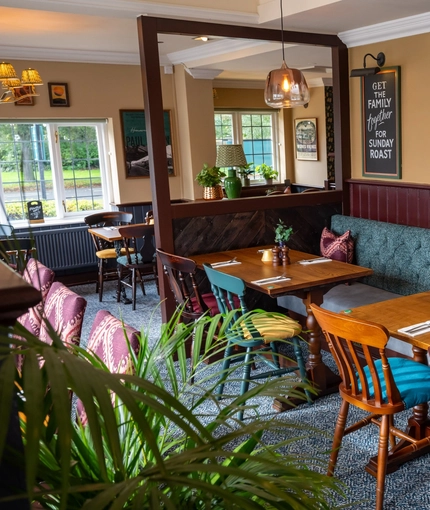 The interior restaurant seating area with tables, chairs, cushioned seating and hanging pendant lighting at The Church View Inn.