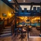 A view of a ground floor interior restaurant seating area at the Old School House, a ground floor games area with gaming machines, and a wooden staircase leading up the upper floor and balcony above.