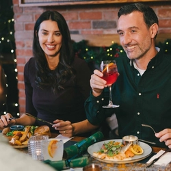 An image of a group of friends enjoying plated Festive mains and various drinks within the interior restaurant seating area of an Urban Core venue.