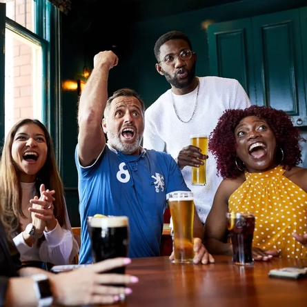 Guests cheering whilst watching live sports in the pub