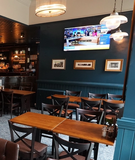 The bar and interior restaurant seating area with TVs, at The Advocate in Edinburgh.