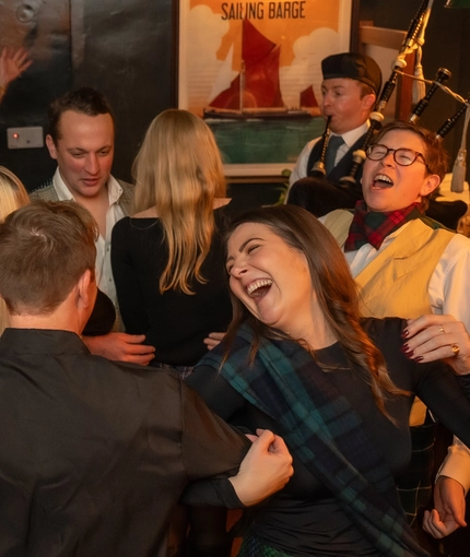 An image of a Bagpipe Player performing as people dance within the interior function room during a Burns Night Event at The Crabtree.