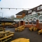 The exterior beer garden seating area at the Wooden Bridge in Guildford, with wooden picnic tables, shade umbrellas, and string lights overhead.